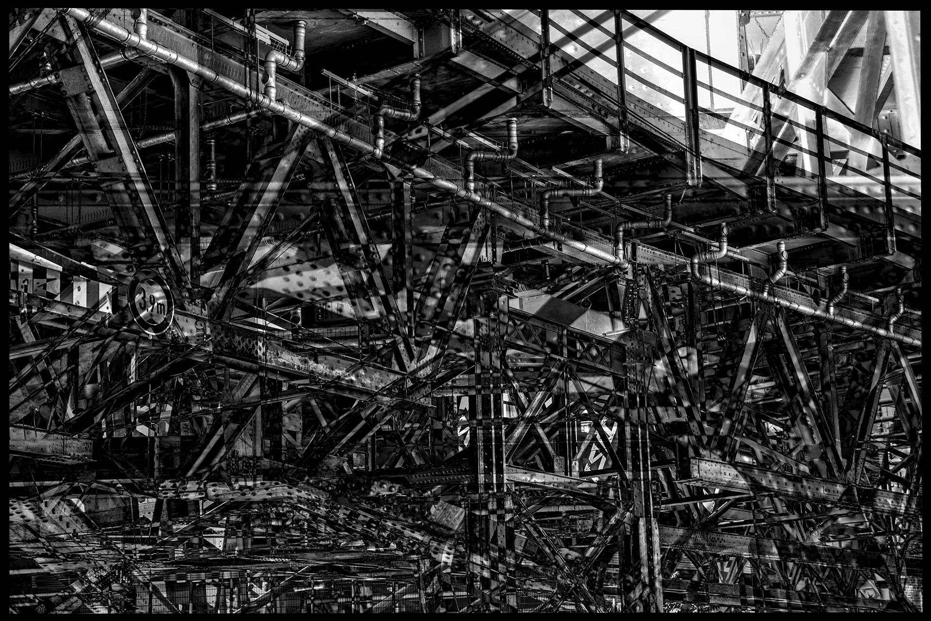 Eine stählerne Brücke mit verwirrenden Unterbau-Konstruktionen. Genietete und verschraubte Eisenträger verdichten sich durch die Verschmelzung mehrerer Momentaufnahmen zu einem technischen Labyrinth.